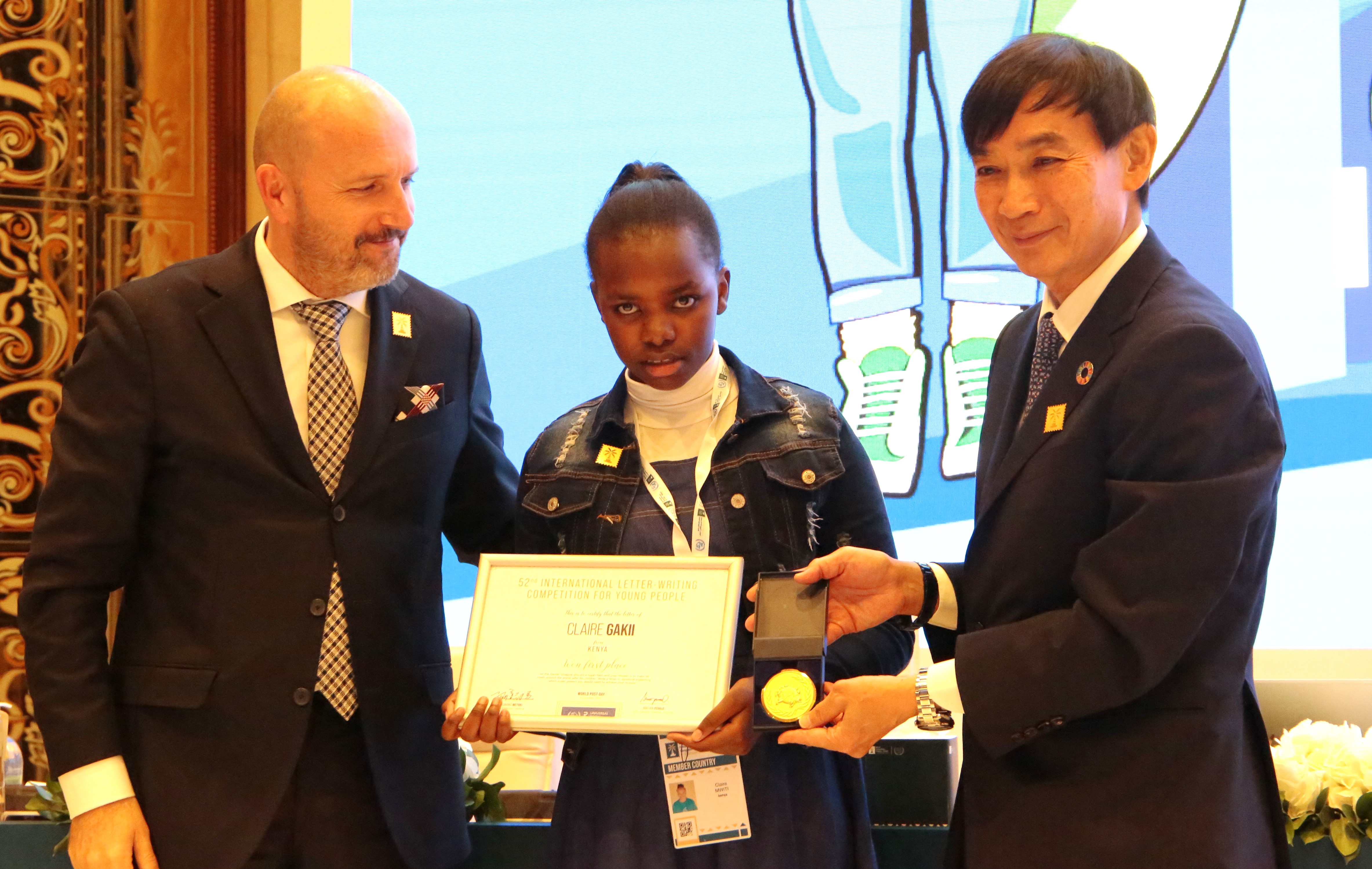 Kenya’s Claire Gakii (centre) receives the award of the winner of the International Letter Writing Competition for Young People from the Universal Postal Union Director General Mr. Masahiko Metoki (right) and his deputy Osvald Marjan in Riyadh, Saudi Arabia. She beat about 1.7 million others to clinch the coveted prize.