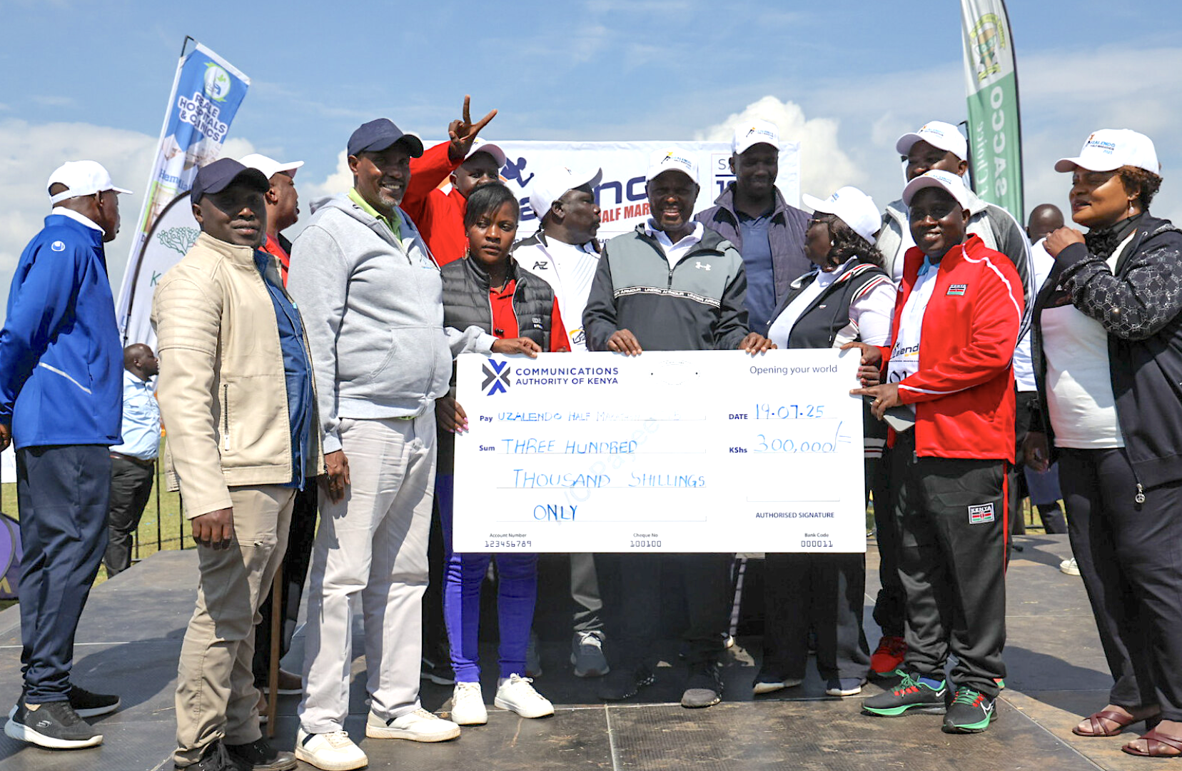 CA staff from the Western Regional Office and board member Hon. Daniel Kipkogei Rono pose with a dummy cheque on Kshs. three hundred thousand presented during the marathon